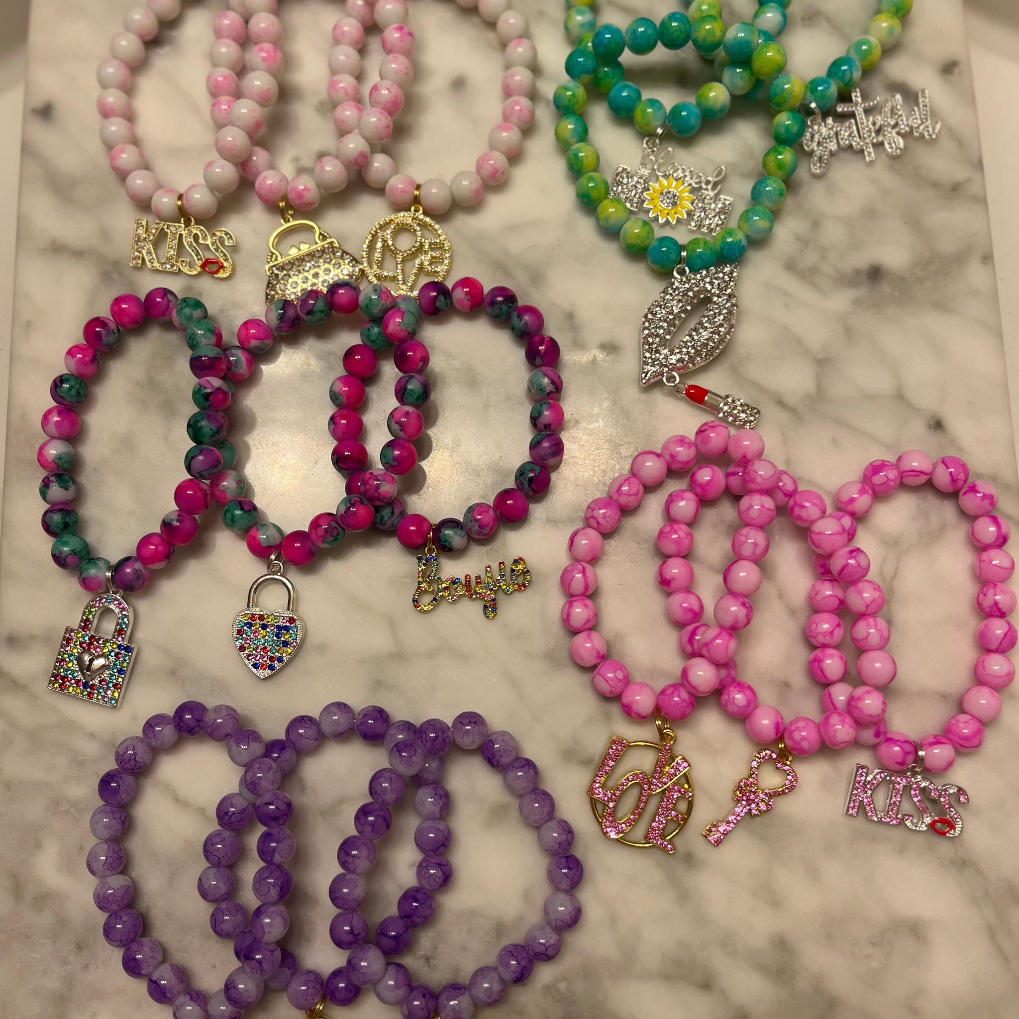 fourteen charm bracelets in colors of white, green, rainbow, pink and purple