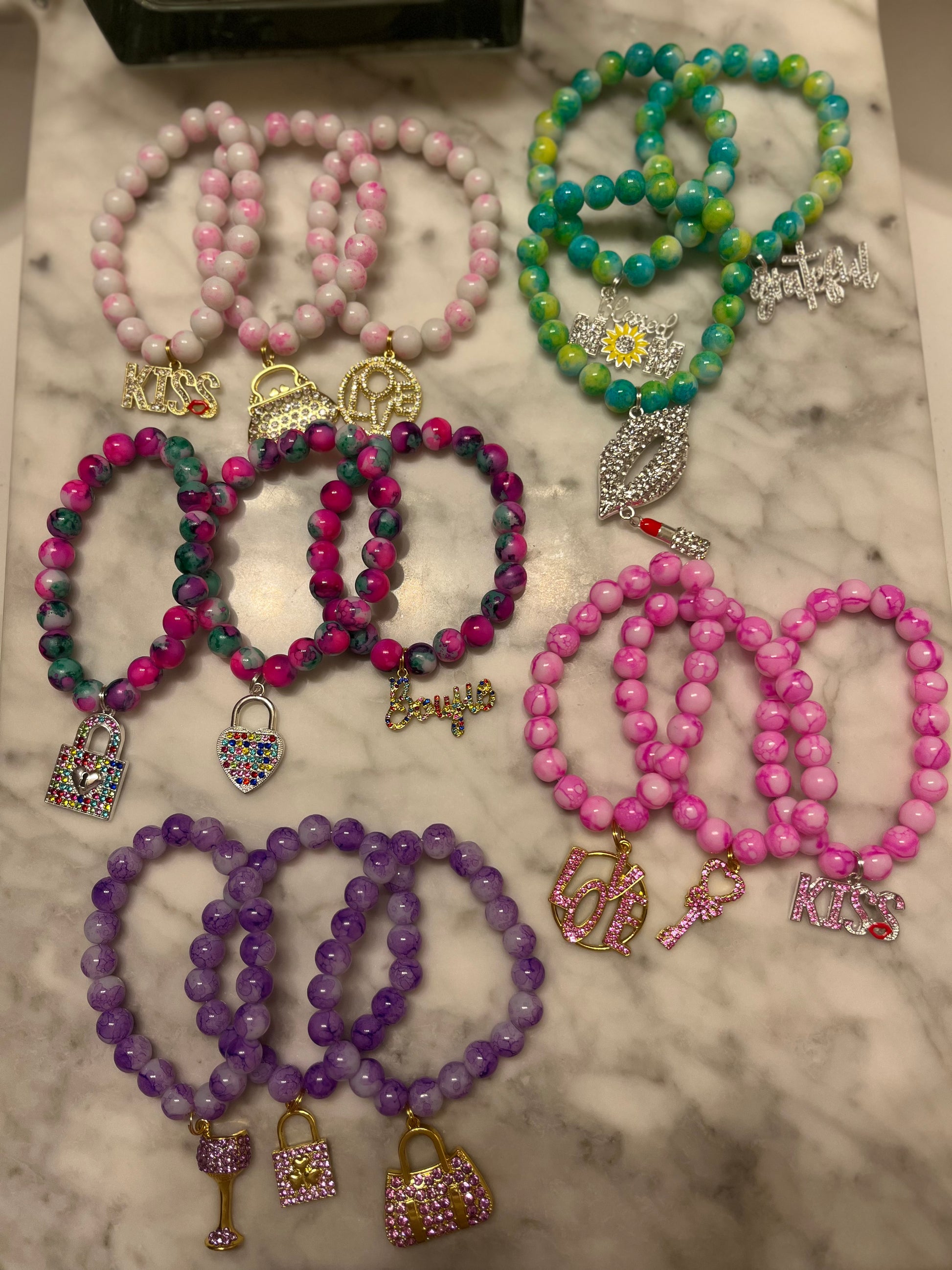 fourteen charm bracelets in colors of white, green, rainbow, pink and purple